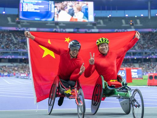 Jin Hua (links) und Dai Yunqiang aus China posieren nach dem 800-m-T54-Finale der Männer in der Para-Leichtathletik bei den Paralympischen Spielen 2024 in Paris