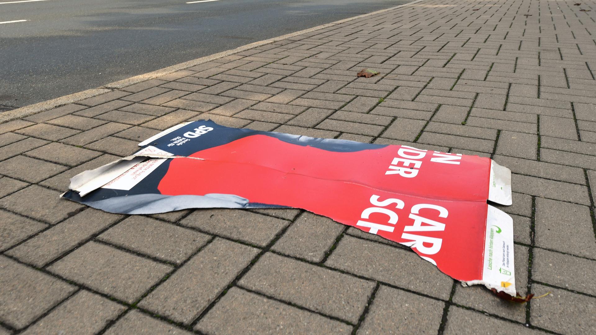 Der abgerissene Teil eines SPD-Wahlplakates liegt auf dem Fußweg.