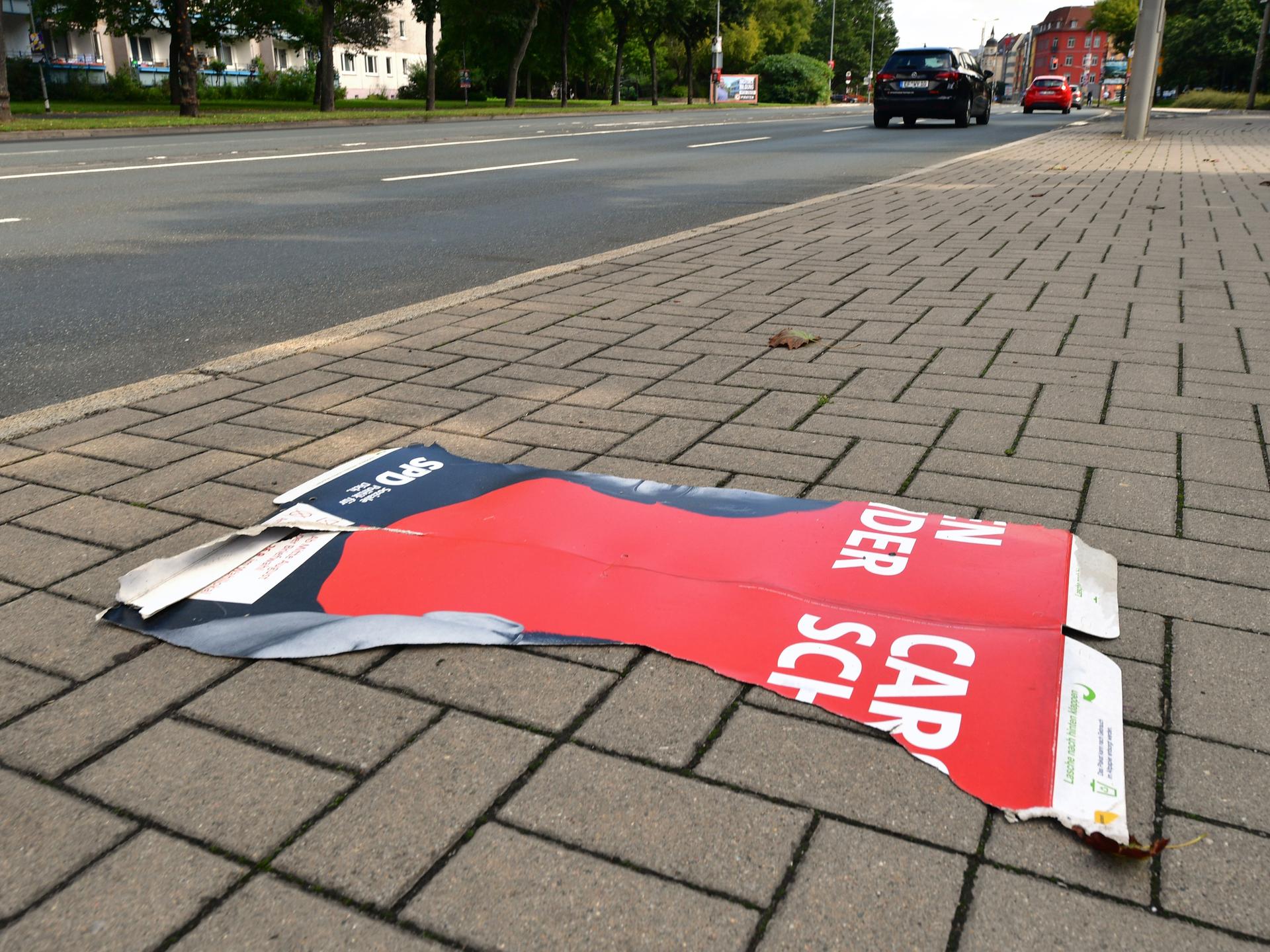 Der abgerissene Teil eines SPD-Wahlplakates liegt auf dem Fußweg.