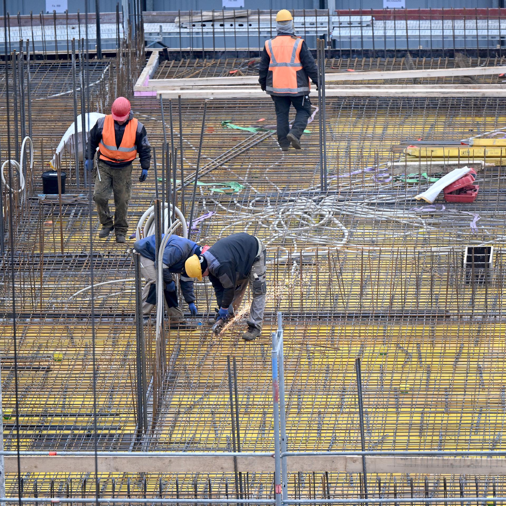 Bauarbeiter auf einer Baustelle, an einem Gebäudekomplex wird am Rohbau gearbeitet.