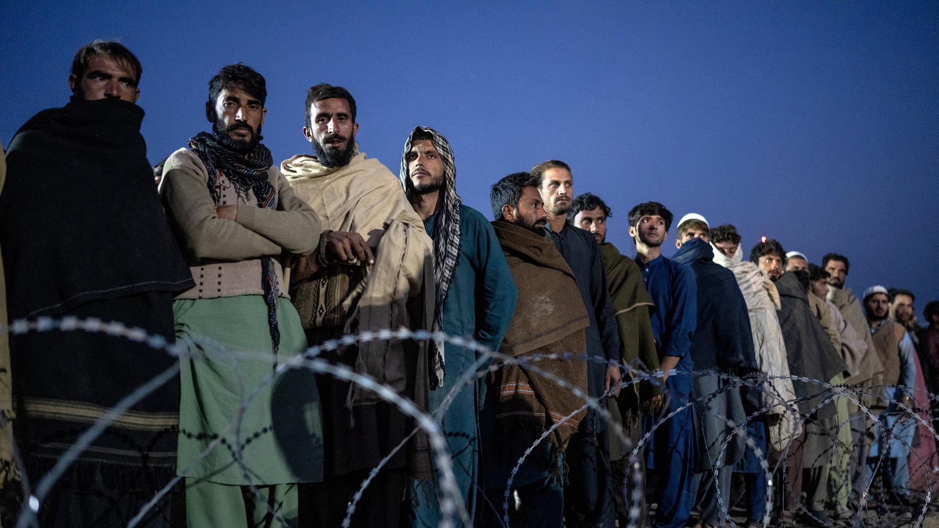 Flüchtlinge aus Afghanistan warten an der Grenze zwischen Afghanistan und Pakistan auf ihre Registrierung und stehen in einer langen Reihe.
