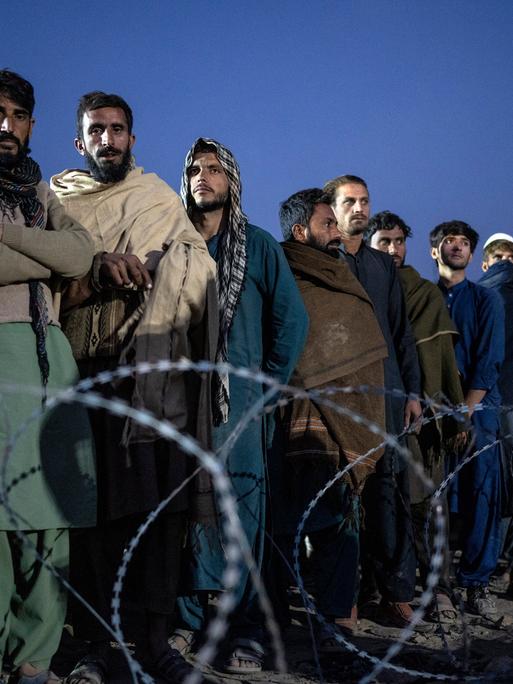 Flüchtlinge aus Afghanistan warten an der Grenze zwischen Afghanistan und Pakistan auf ihre Registrierung und stehen in einer langen Reihe.