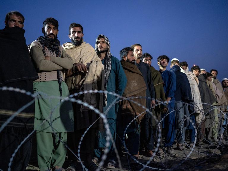 Flüchtlinge aus Afghanistan warten an der Grenze zwischen Afghanistan und Pakistan auf ihre Registrierung und stehen in einer langen Reihe.