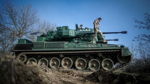 Ein Panzer der Bundeswehr steht auf einem Feld. Soldaten stehen auf dem Panzer.