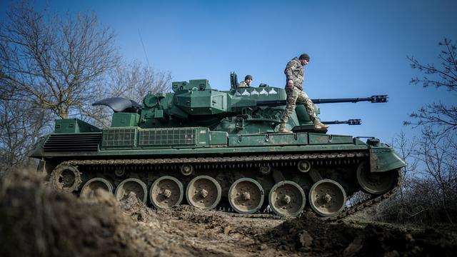 Ein Panzer von der Bundes-Wehr steht auf einem Feld. Soldaten stehen auf dem Panzer.