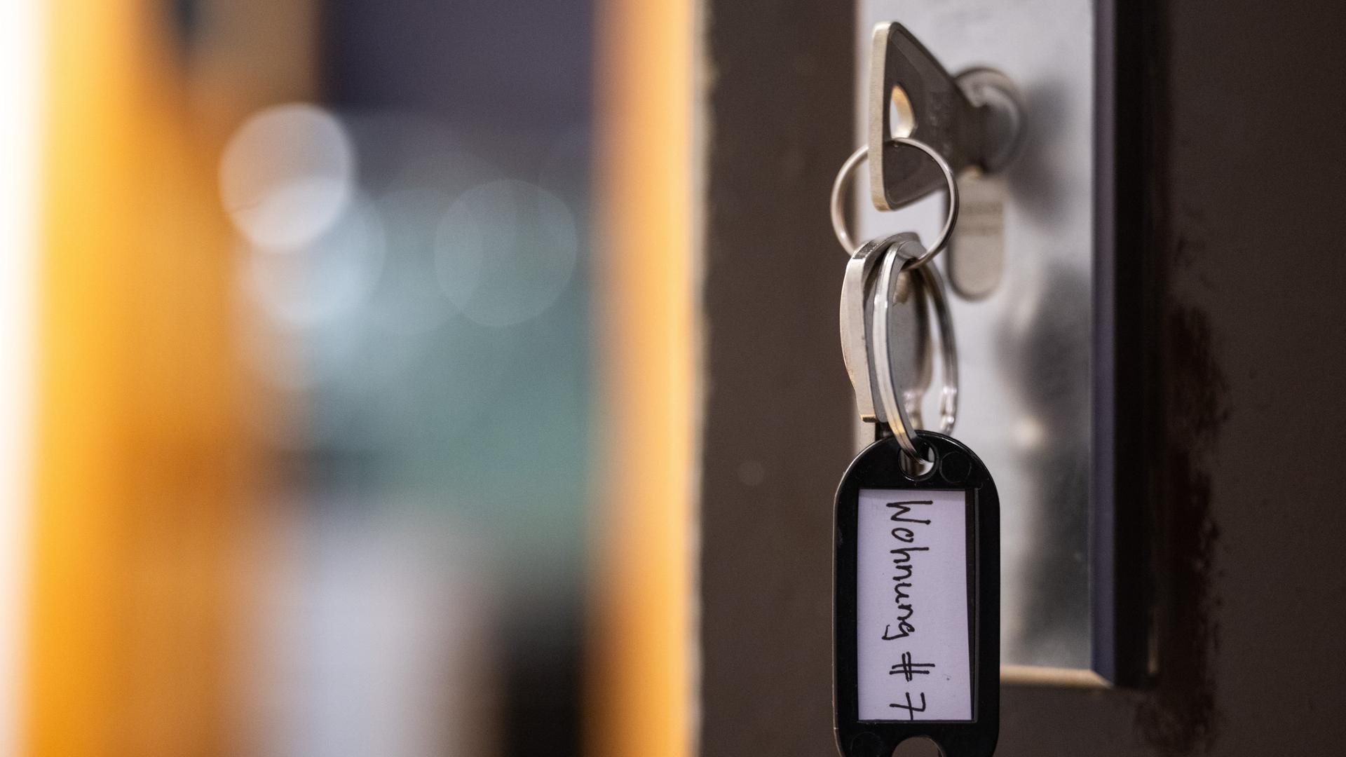 Ein Schlüssel mit der Aufschrift "Wohnung #7" hängt an einer Wohnungseingangstür. Ein Schlüssel mit der Aufschrift "Wohnung #7" hängt an einer Wohnungseingangstür.