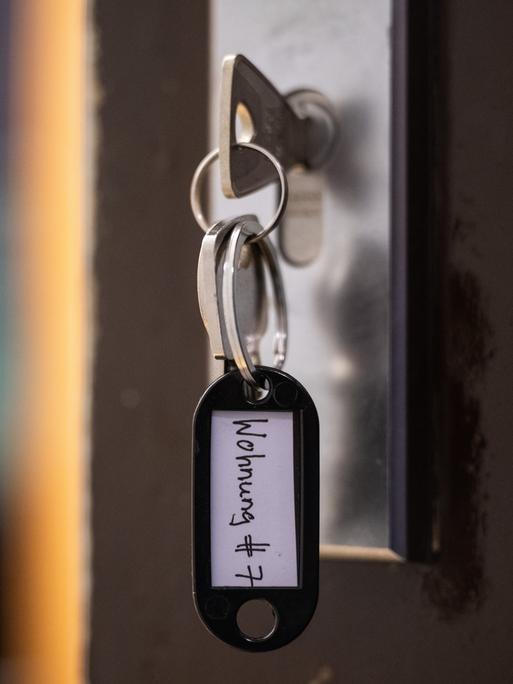 Ein Schlüssel mit der Aufschrift "Wohnung #7" hängt an einer Wohnungseingangstür. 