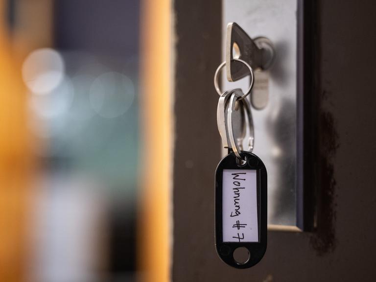 Ein Schlüssel mit der Aufschrift "Wohnung #7" hängt an einer Wohnungseingangstür. 