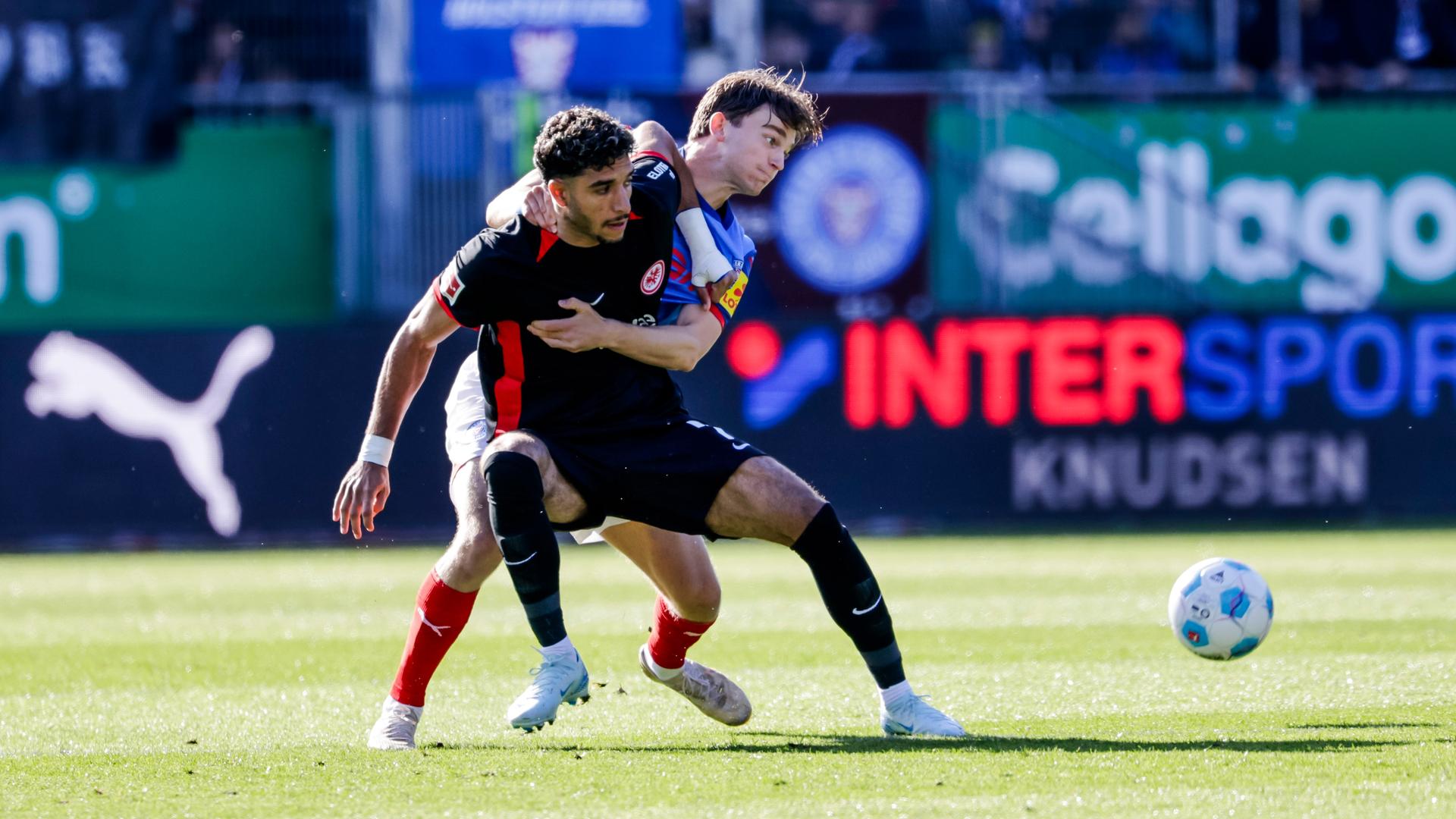 Fußball-Szene aus der Bundesligapartie Holstein Kiel gegen Eintracht Frankfurt: Im Holstein-Stadion kämpfen Frankfurts Omar Marmoush (links) und Kiels Magnus Knudsen um den Ball.