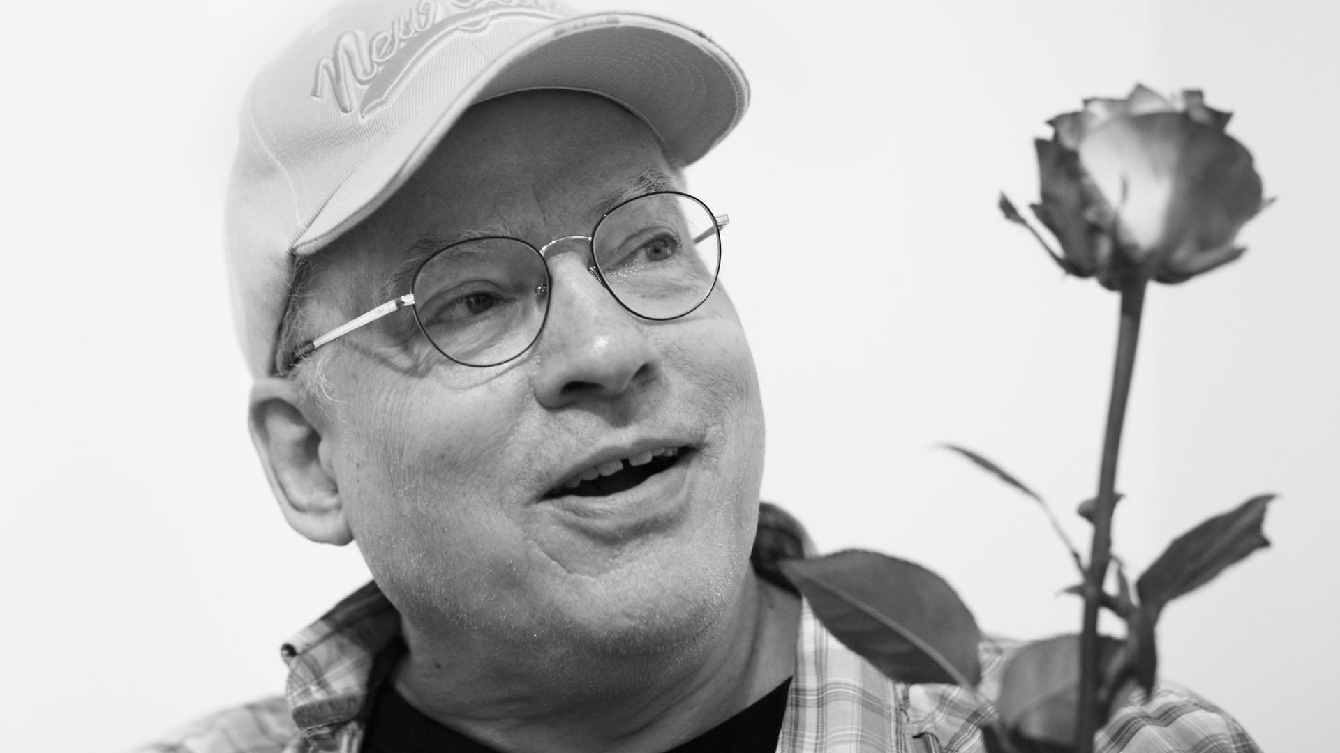 Der Filmemacher, Autor, Künstler und Schwulenaktivist Rosa von Praunheim hält eine Rose in der Hand.