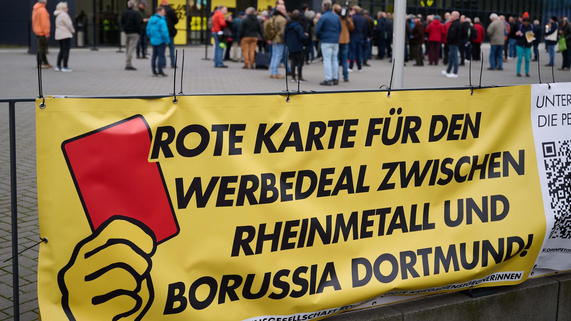 Ein Transparent der "Deutschen Friedensgesellschaft - Vereinte KriegsdienstgegnerInnen" mit der Aufschrift "Rote Karte für den Werbedeal zwischen Rheinmetall und Borussia Dortmund" hängt vor dem Eingang der Versammlungshalle.