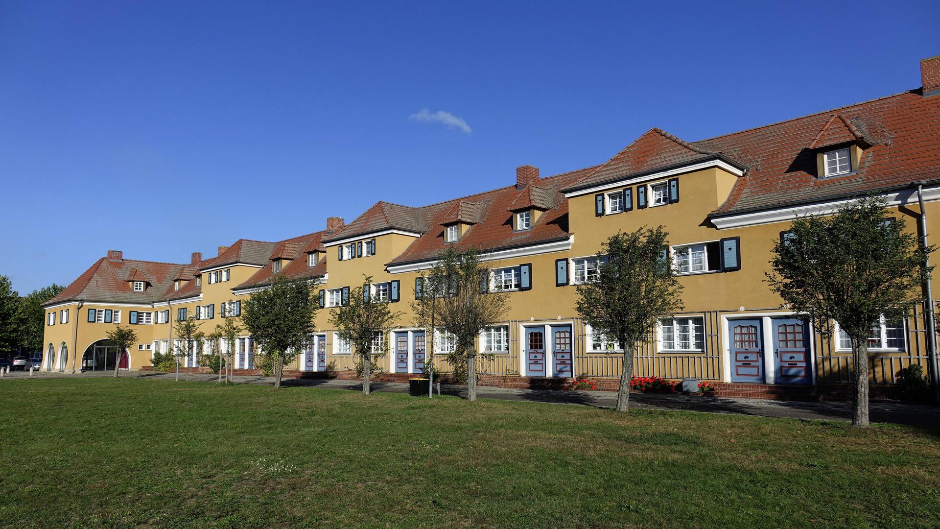 Die Priesteritzer Werkssiedlung in Sachsen-Anhalt - ein ockerfarben gestrichener, dreigeschossiger Wohnblock von 1916 mit blauen Fensterläden.