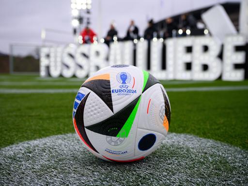 Der neue Fußball liegt bei der Vorstellung des EM-Spielballs für die UEFA EURO 2024 auf dem Maifeld am Olympiastadion. Im Hintergrund sieht verschwommen in großen weißen Lettern den Namen "Fussballliebe".