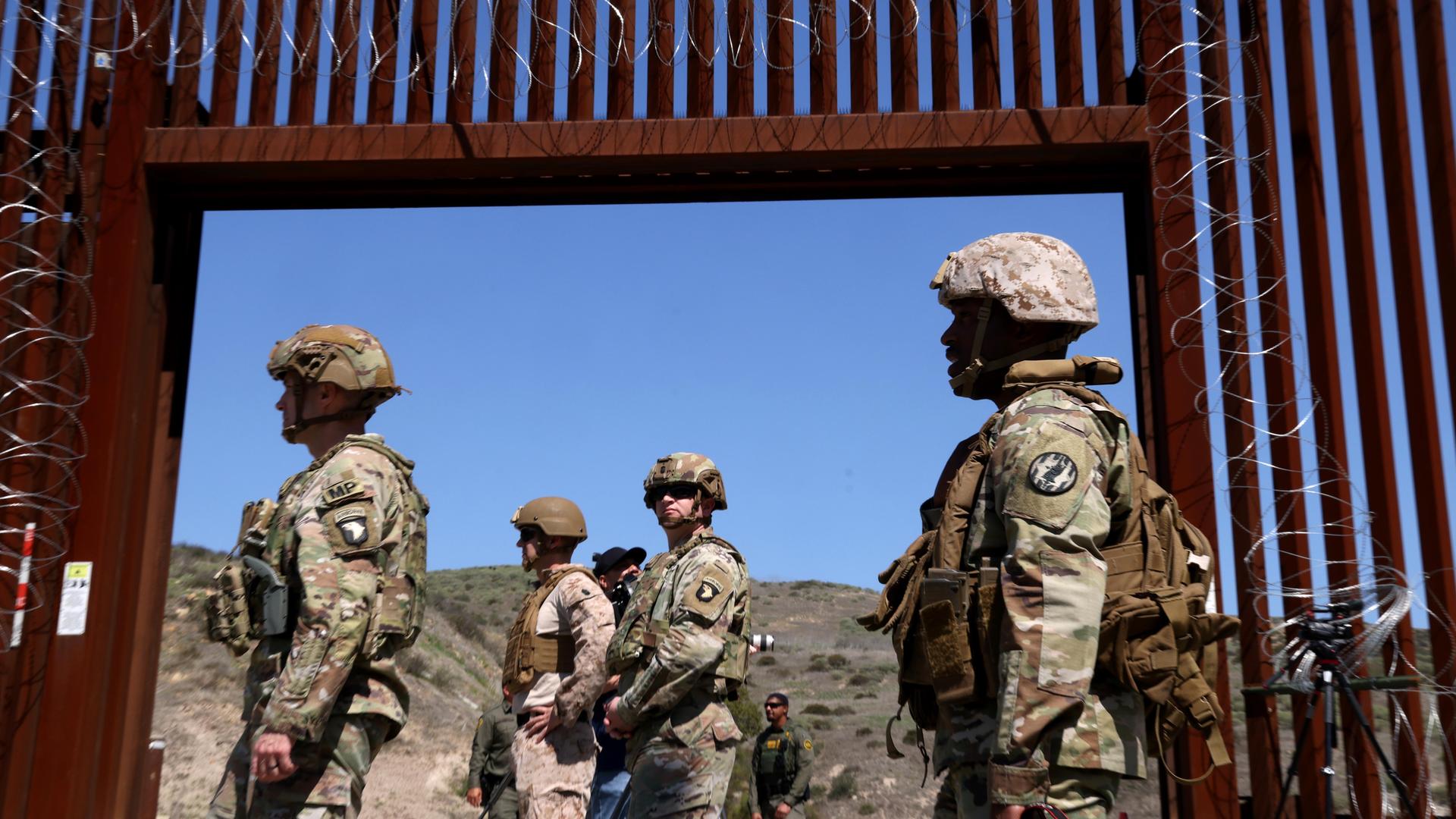 Mitglieder des US-Militärs stehen am 21. März 2025 vor einem offenen Tor an der Mauer entlang der Grenze zwischen den USA und Mexiko in der Nähe von San Ysidro. 