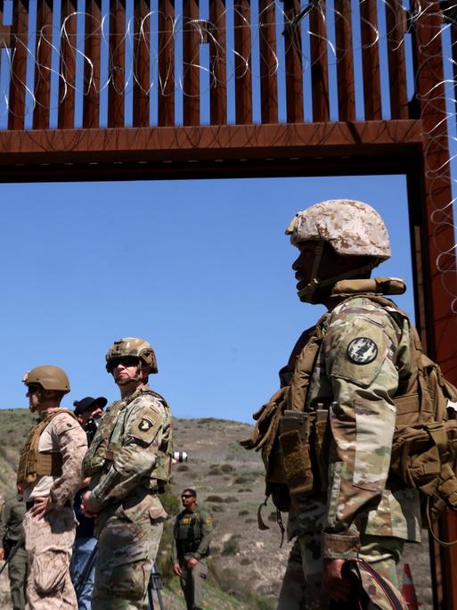 Mitglieder des US-Militärs stehen am 21. März 2025 vor einem offenen Tor an der Mauer entlang der Grenze zwischen den USA und Mexiko in der Nähe von San Ysidro. 