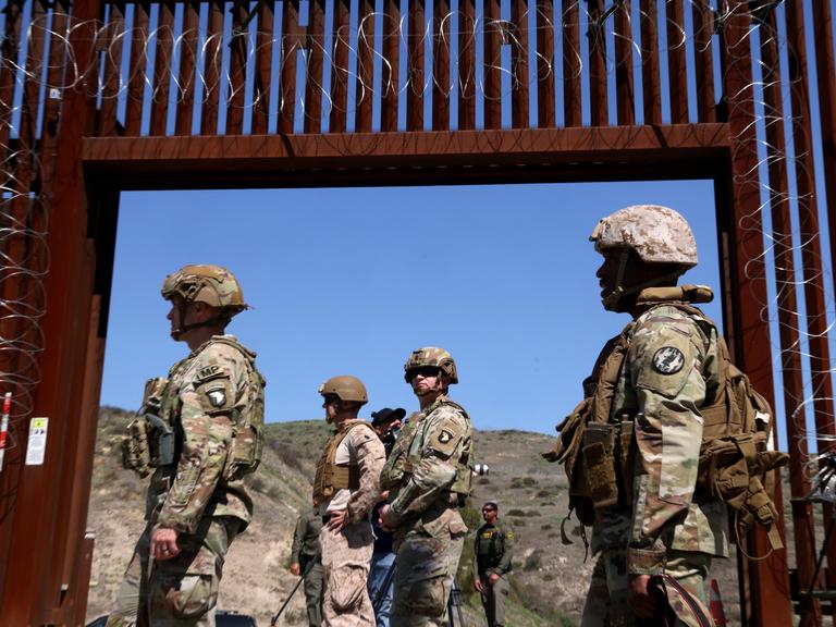 Mitglieder des US-Militärs stehen am 21. März 2025 vor einem offenen Tor an der Mauer entlang der Grenze zwischen den USA und Mexiko in der Nähe von San Ysidro. 