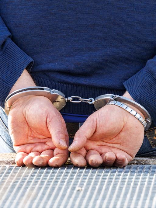 Ein Mann trägt Handschellen nach seiner Festnahme durch die Polizei