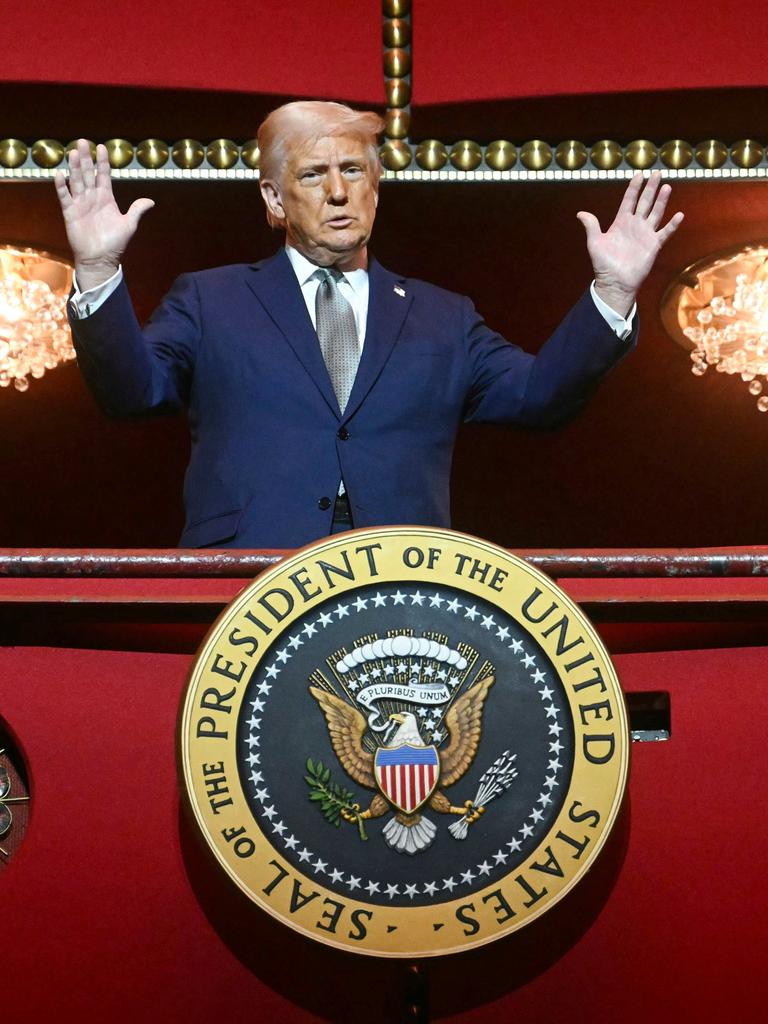 US-Präsident Donald Trump steht mit erhobenen Armen zwischen zwei Kronleuchtern in einer Loge des Kennedy Center in Washington, an der Brüstung ist ein rundes Schild mit dem Präsidentenwappen angebracht: Seal of the President of the United States.