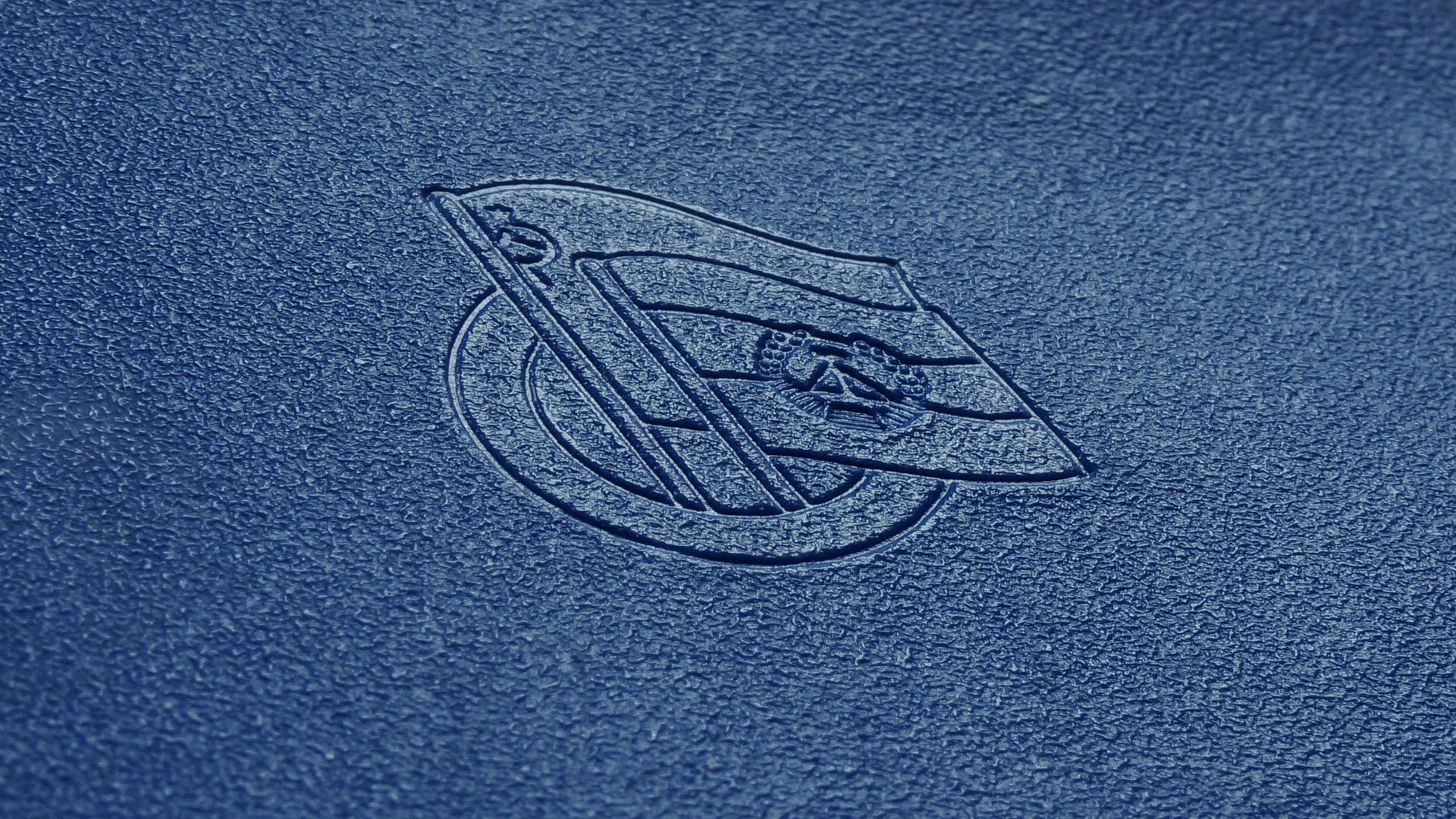 Geprägtes Logo mit sowjetischer und DDR-Flagge auf dem blauen Einband des Mitgliedsbuchs der Gesellschaft für Deutsch-Sowjetische Freundschaft.