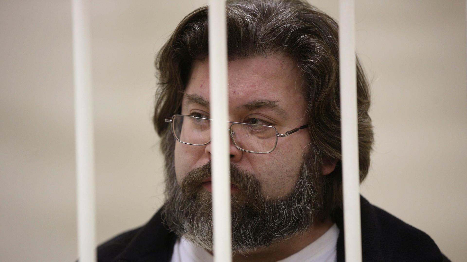 Der russische Menschenrechtsaktivist Roman Dolgov steht hinter den Gittern einer Gefängniszelle. Der russische Menschenrechtsaktivist Roman Dolgov steht hinter den Gittern einer Gefängniszelle.