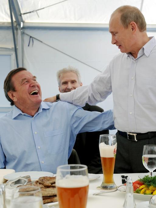 Der damalige Vorstandsvorsitzende der Nord Stream AG, Bundeskanzler a. D. Gerhard Schröder und der russische Ministerpräsident Wladimir Putin (v.l.n.r.) treffen sich an der Portovaya-Kompressorstation in Vyborg bei Bier und bester Laune.
