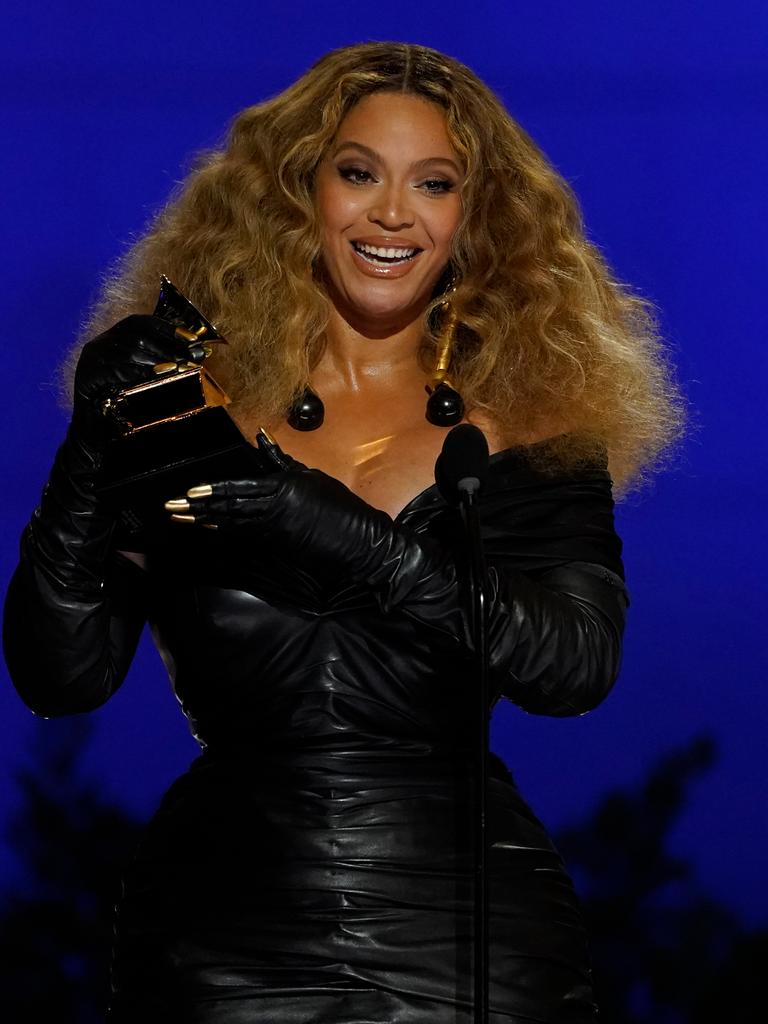 Musikerin Beyoncé steht in schwarzem Kleid vor blauem Hintergrund