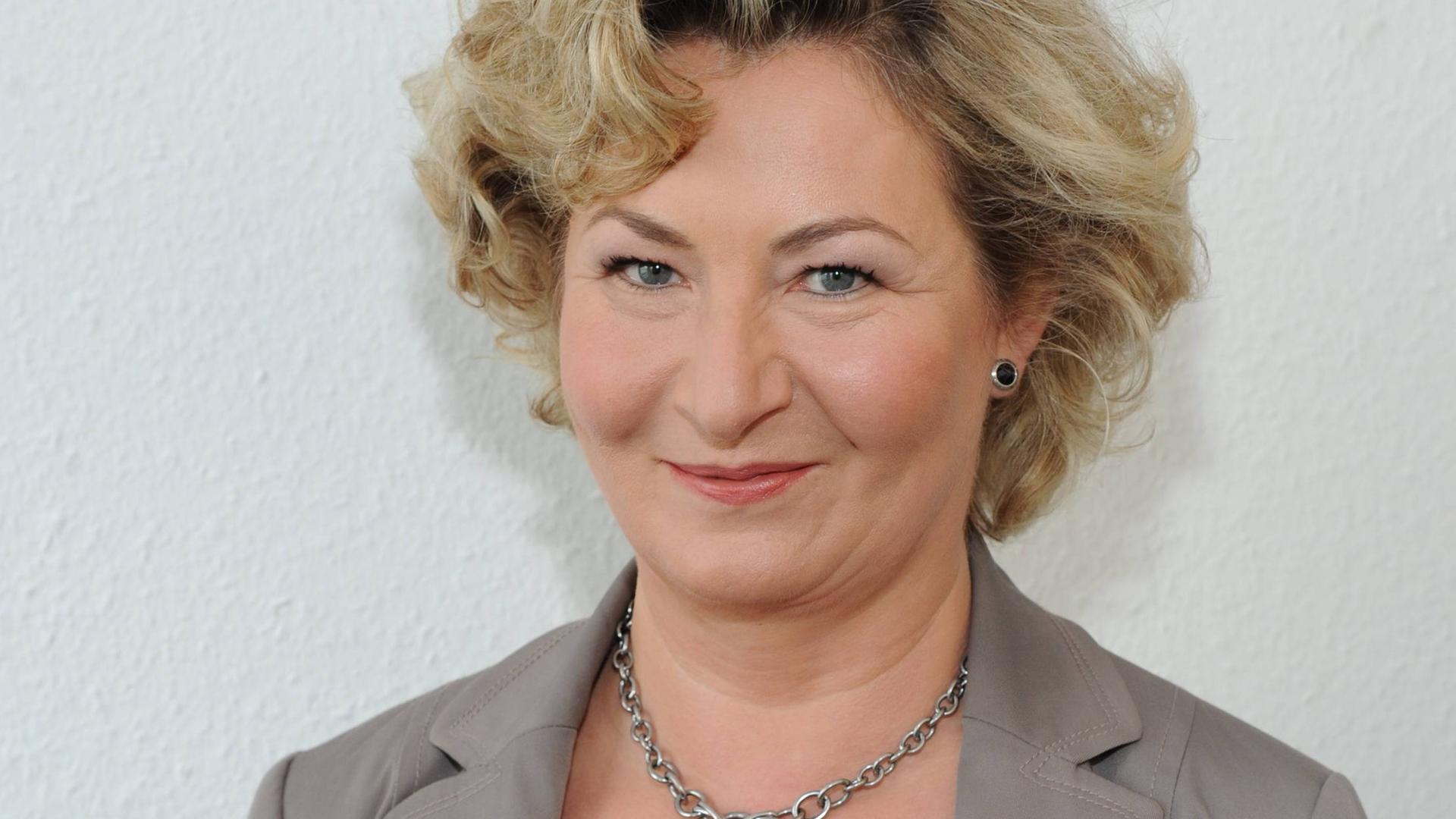 Ada Borkenhagen lächelt in die Kamera. Sie hat kurze blonde Locken und trägt einen grauen Blazer.