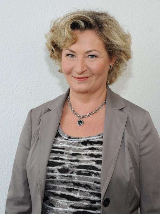 Ada Borkenhagen lächelt in die Kamera. Sie hat kurze blonde Locken und trägt einen grauen Blazer.