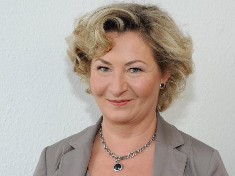 Ada Borkenhagen lächelt in die Kamera. Sie hat kurze blonde Locken und trägt einen grauen Blazer.