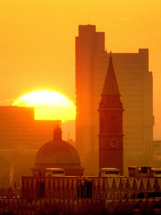 Blick auf die aufgehende Sonne über der Skyline von München