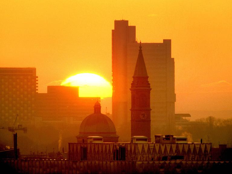 Blick auf die aufgehende Sonne über der Skyline von München