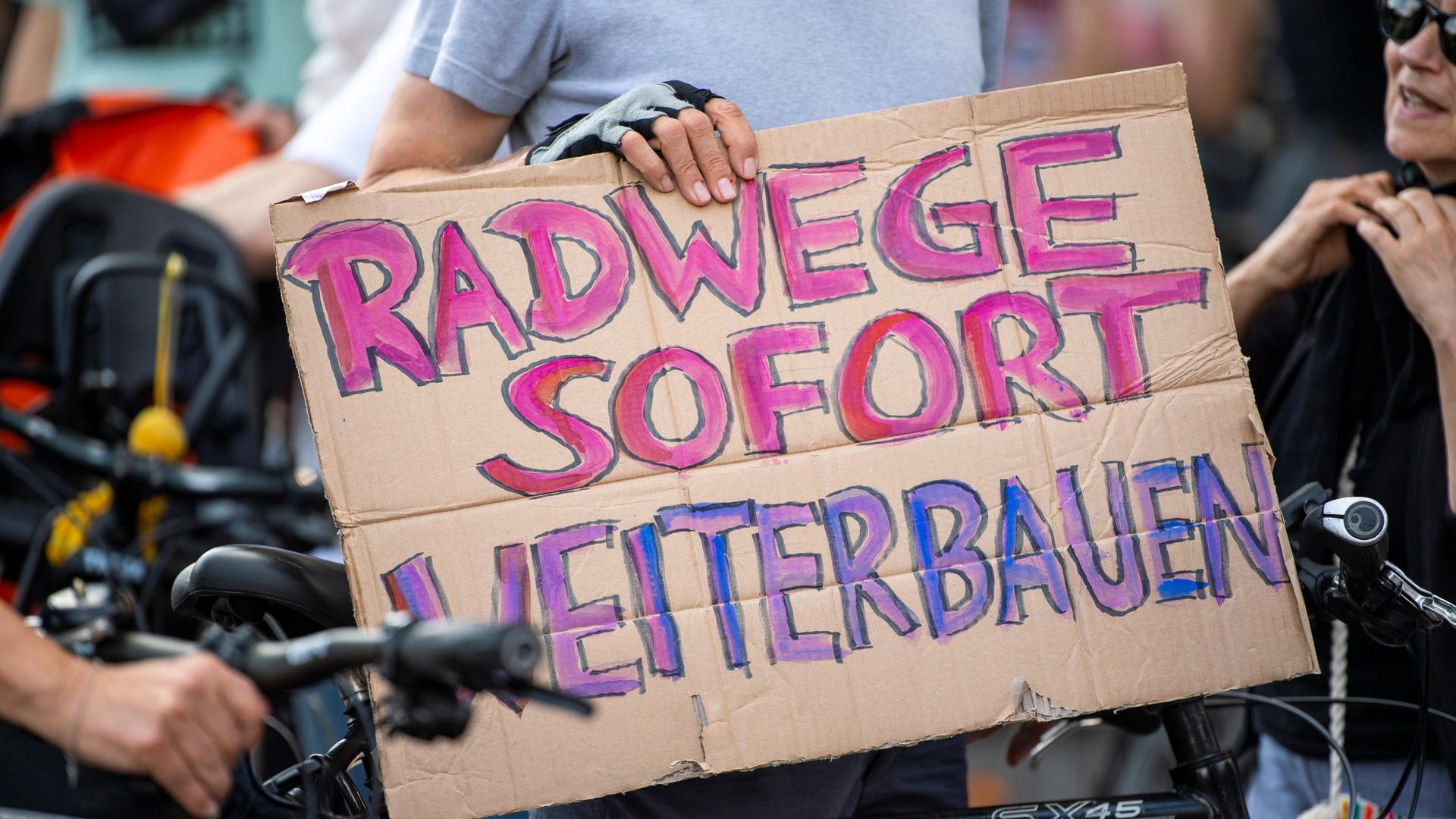 Ein Teilnehmer einer Demonstration gegen Einschränkungen beim Radwegeausbau in Berlin hält bei einer Abschlusskundgebung vor dem Roten Rathaus ein Plakat mit der Aufschrift "Radwege sofort weiterbauen".