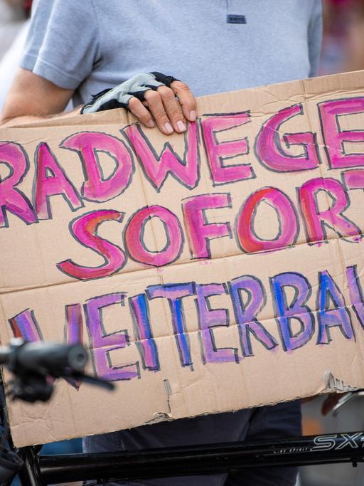 Ein Teilnehmer einer Demonstration gegen Einschränkungen beim Radwegeausbau in Berlin hält bei einer Abschlusskundgebung vor dem Roten Rathaus ein Plakat mit der Aufschrift "Radwege sofort weiterbauen".