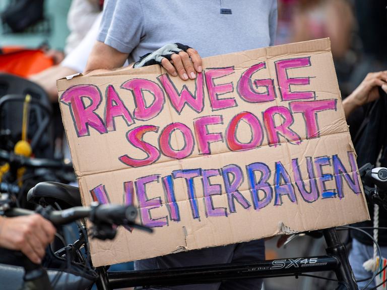 Ein Teilnehmer einer Demonstration gegen Einschränkungen beim Radwegeausbau in Berlin hält bei einer Abschlusskundgebung vor dem Roten Rathaus ein Plakat mit der Aufschrift "Radwege sofort weiterbauen".