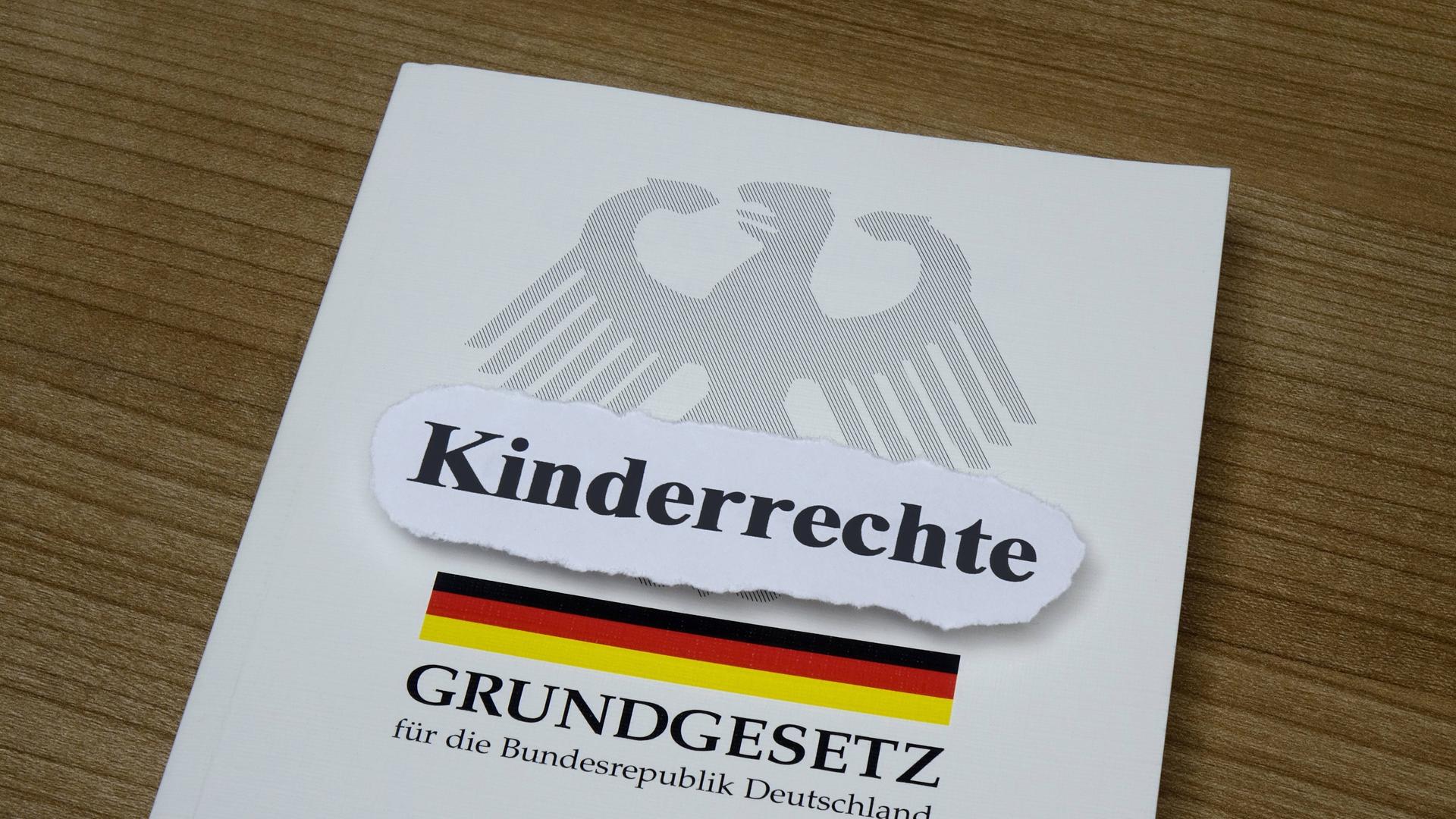 Auf dem Grundgesetz ist ein Aufkleber mit dem Wort "Kinderrechte" angebracht. Auf dem Grundgesetz ist ein Aufkleber mit dem Wort "Kinderrechte" angebracht.