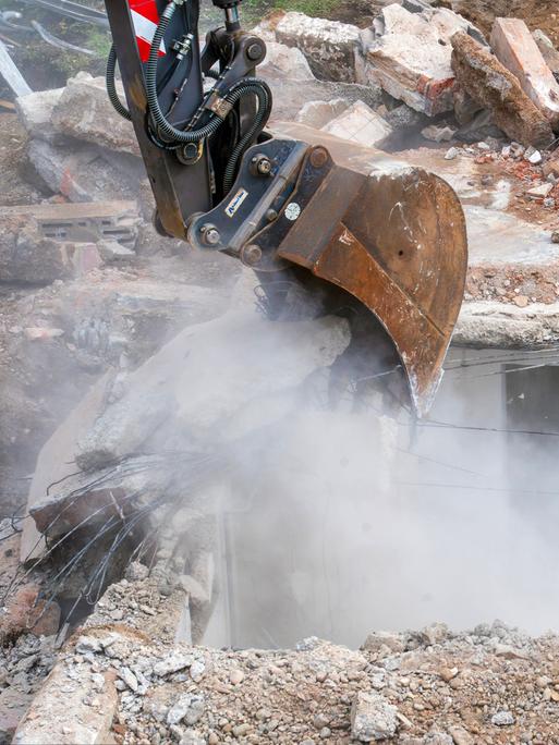 Abbruch eines alten Einfamilienhauses, Bagger hebt Fundament und Keller aus