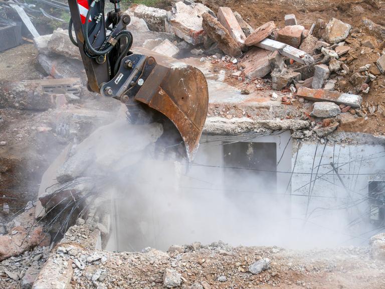 Abbruch eines alten Einfamilienhauses, Bagger hebt Fundament und Keller aus