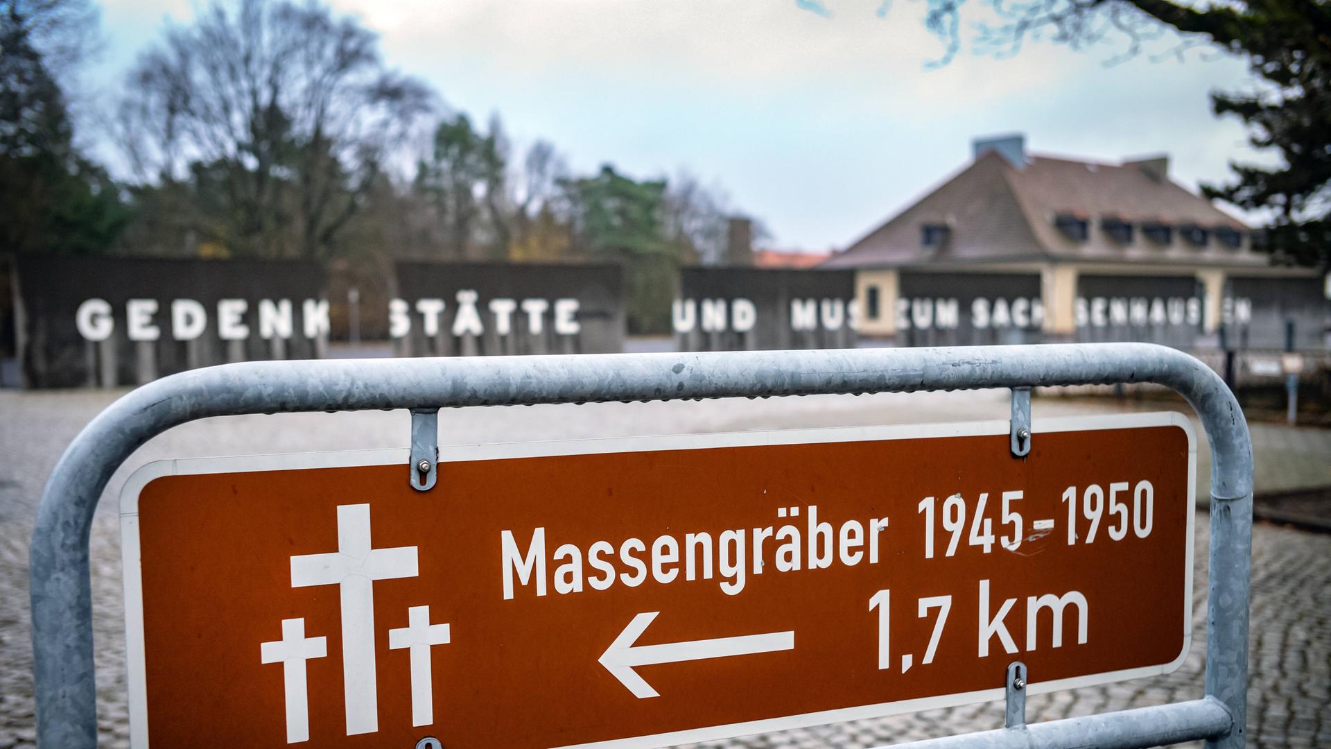 Die KZ-Gedänkstätte Sachsenhausen. Auf einem Schild im Vordergrund steht "Massengräber 1945-1950 in 1,7 km". Im Hintergrund sieht man den Eingang zur Gedenkstätte mit dem Schriftzug "Gedenkstätte und Museum Sachsenhausen". Die KZ-Gedänkstätte Sachsenhausen. Auf einem Schild im Vordergrund steht "Massengräber 1945-1950 in 1,7 km". Im Hintergrund sieht man den Eingang zur Gedenkstätte mit dem Schriftzug "Gedenkstätte und Museum Sachsenhausen".