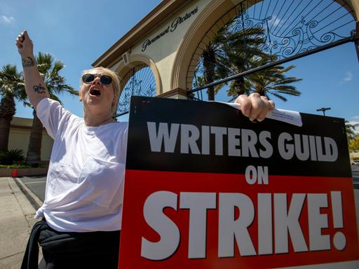 Vor den Paramount Studios in Los Angeles protestiert ein Mitglied der US-Autorengewerkschaft mit einem großen Plakat.