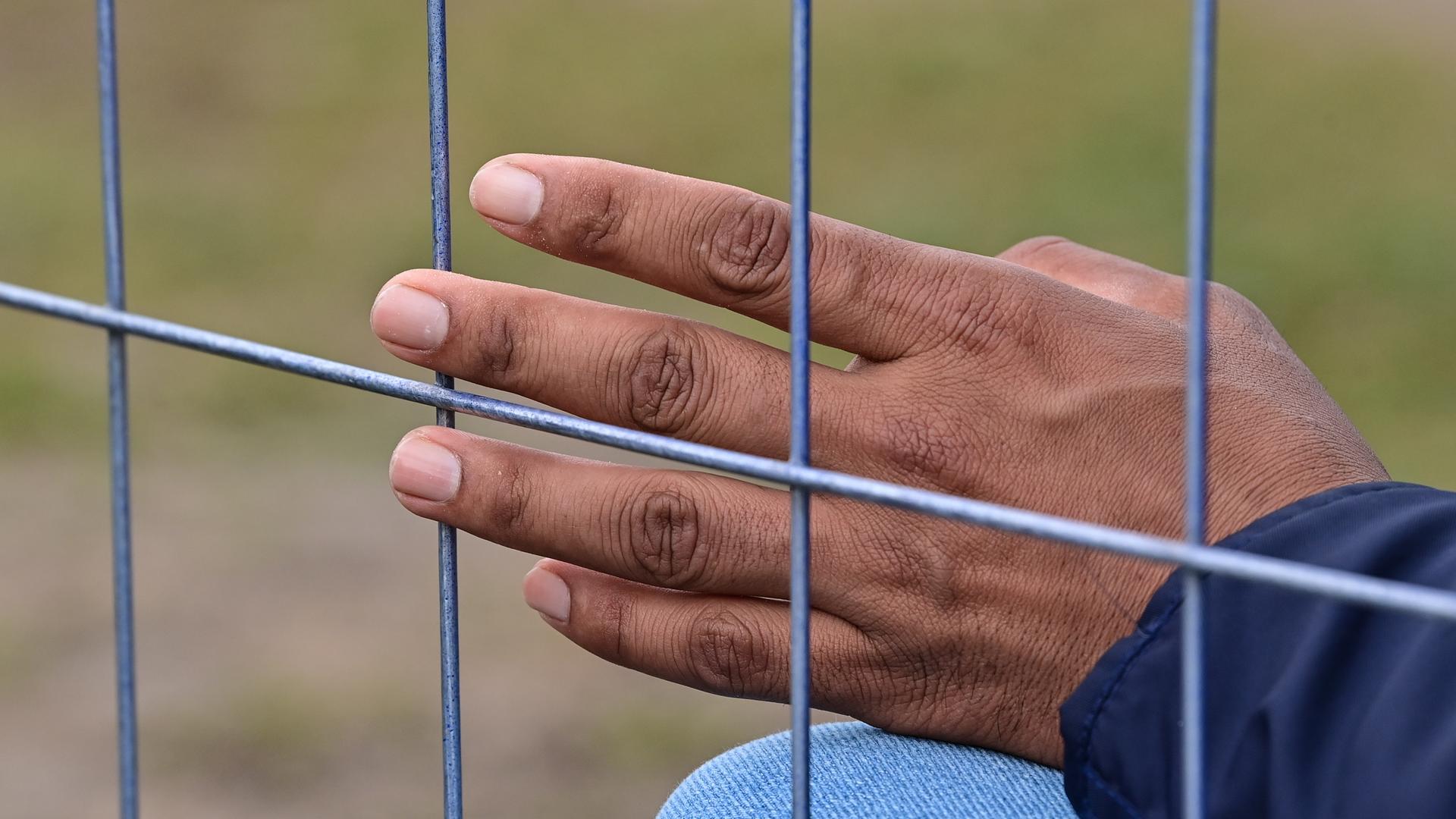 Die Hand eines Flüchtlings ist an einem Zaun der Zentralen Erstaufnahmeeinrichtung für Asylbewerber (ZABH) des Landes Brandenburg zu sehen.