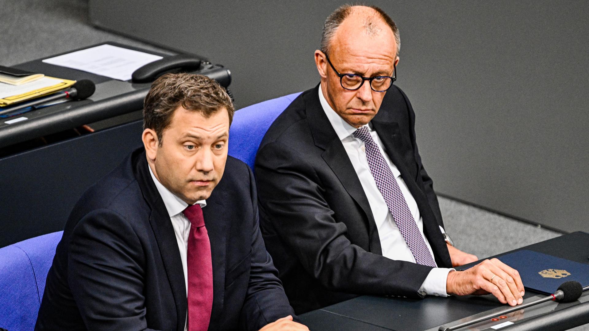 Bundeskanzler Friedrich Merz (r, CDU) und Vizekanzler Lars Klingbeil (SPD) sitzen nebeneinander auf der Regierungsbank im Deutschen Bundestag.