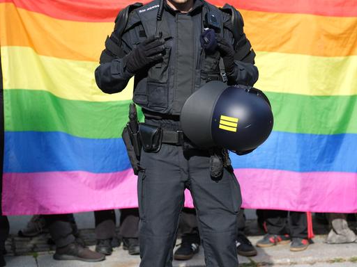 Ein Polizist steht vor einer Regenbogenfahne während eines Umzuges zum Christopher-Street-Day (CSD) in Bautzen