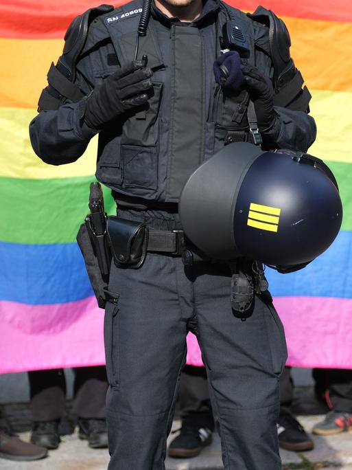 Ein Polizist steht vor einer Regenbogenfahne während eines Umzuges zum Christopher-Street-Day (CSD) in Bautzen