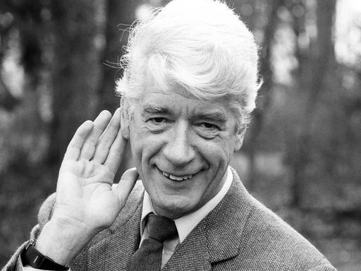 Rudi Carrell legt sich eine Hand hinters Ohr und lächelt freundlich in die Kamera.