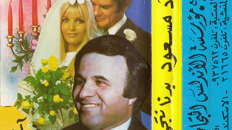 Ein Kassettencover zeigt ein Hochzeitspaar und im Vordergrund einen lächelnden Mann mit Sakko und Fliege.