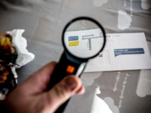 Eine Hand hält eine Lupe und vergrößert den Schriftzug "Deutsche Rentenversicherung", der auf einem Briefumschlag gedruckt ist.