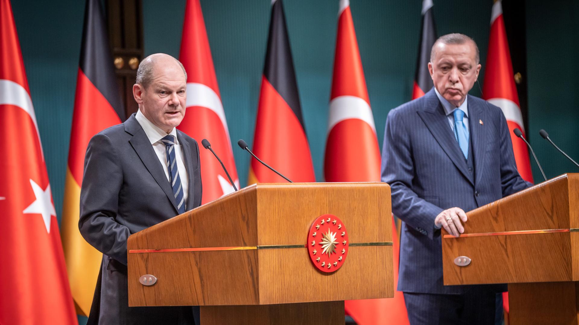 Die beiden stehen nebeneinander an Rednerpult; Scholz spricht. Dahinter mehrere Flaggen beider Länder.