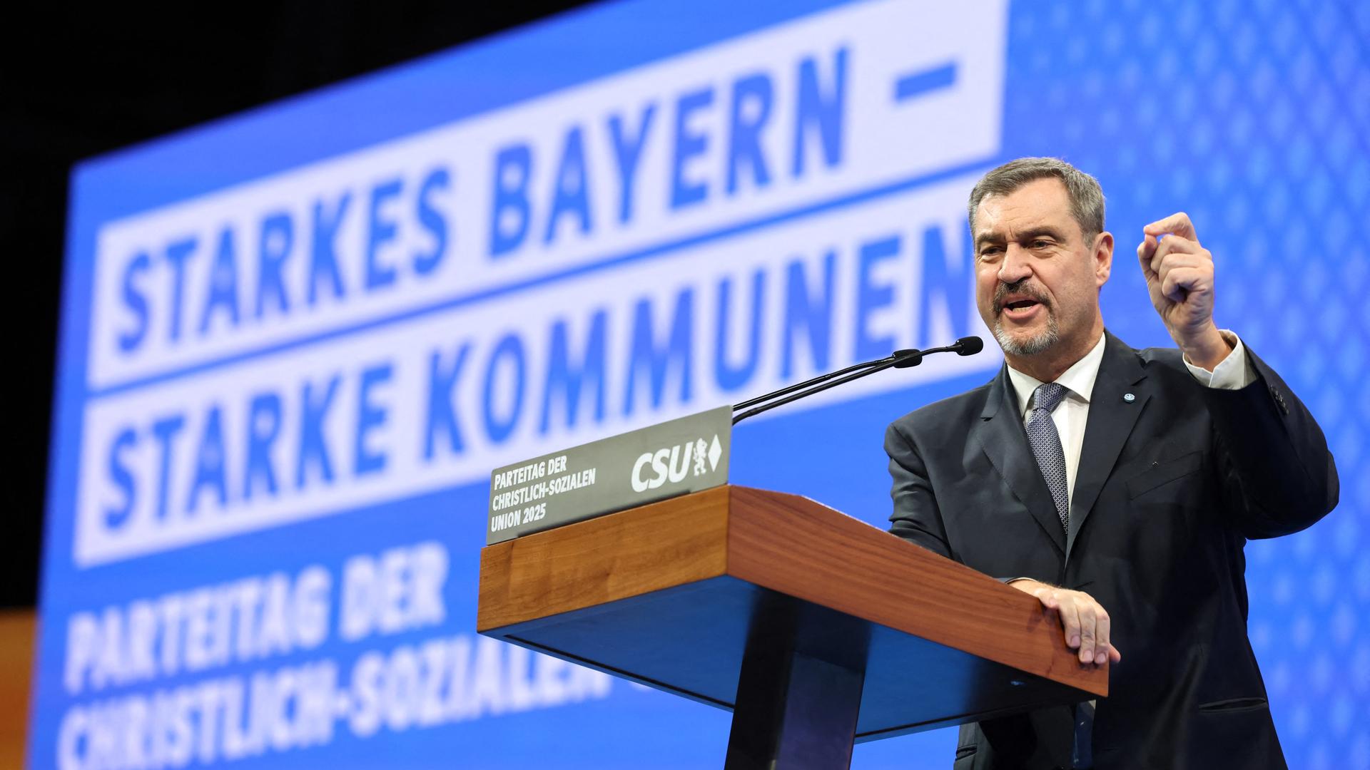 CSU-Chef Söder steht an einem Rednerpult und hebt die linke Hand, um seinen Worten Nachdruck zu verleihen. Im Hintergrund sieht man auf einer großen Tafel das Motto: Starkes Bayern - Starke Kommunen CSU-Chef Söder steht an einem Rednerpult und hebt die linke Hand, um seinen Worten Nachdruck zu verleihen. Im Hintergrund sieht man auf einer großen Tafel das Motto: Starkes Bayern - Starke Kommunen