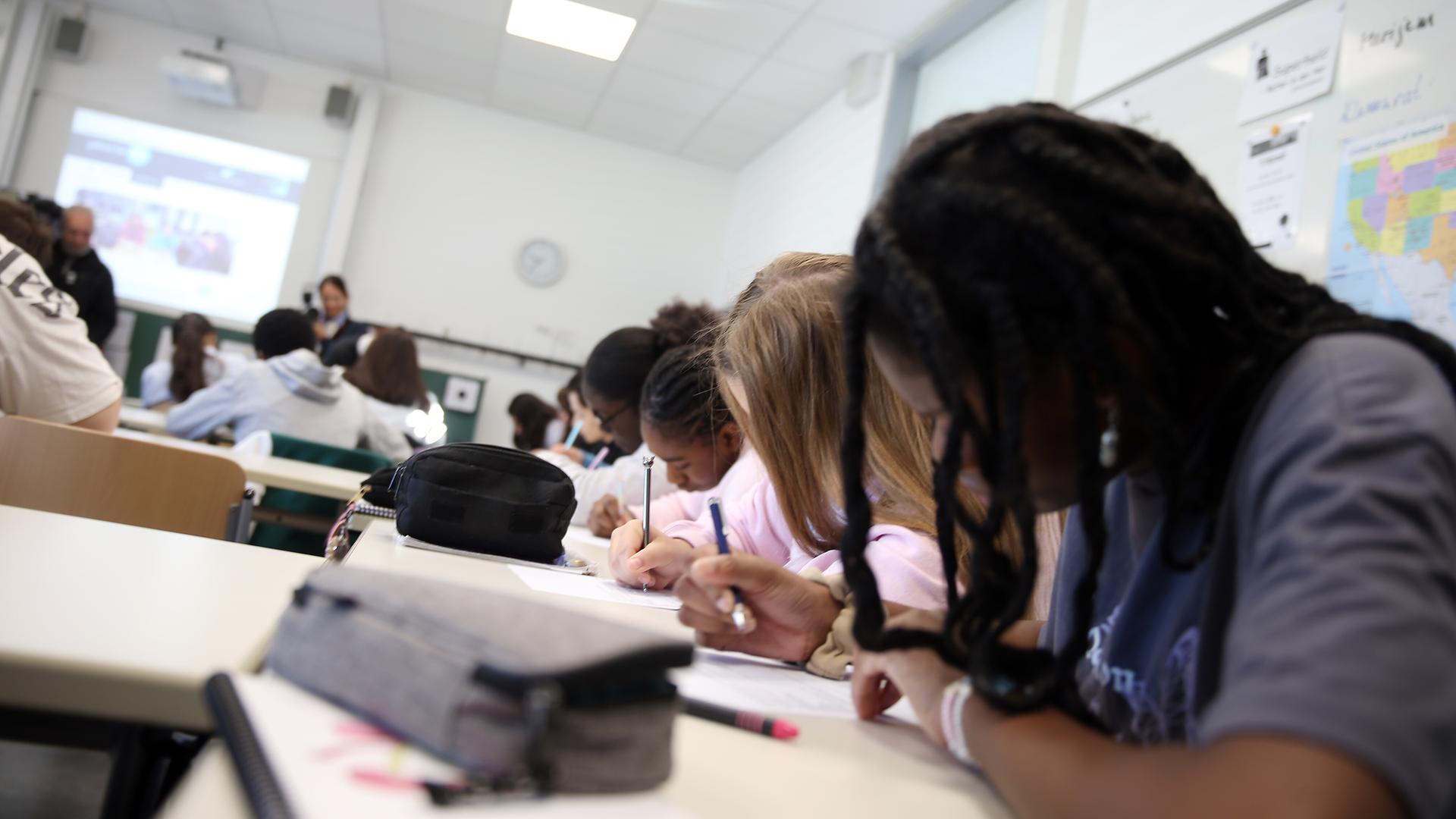 Schüler sitzen während des Unterrichts nebeneinander in einer Klasse und schreiben.