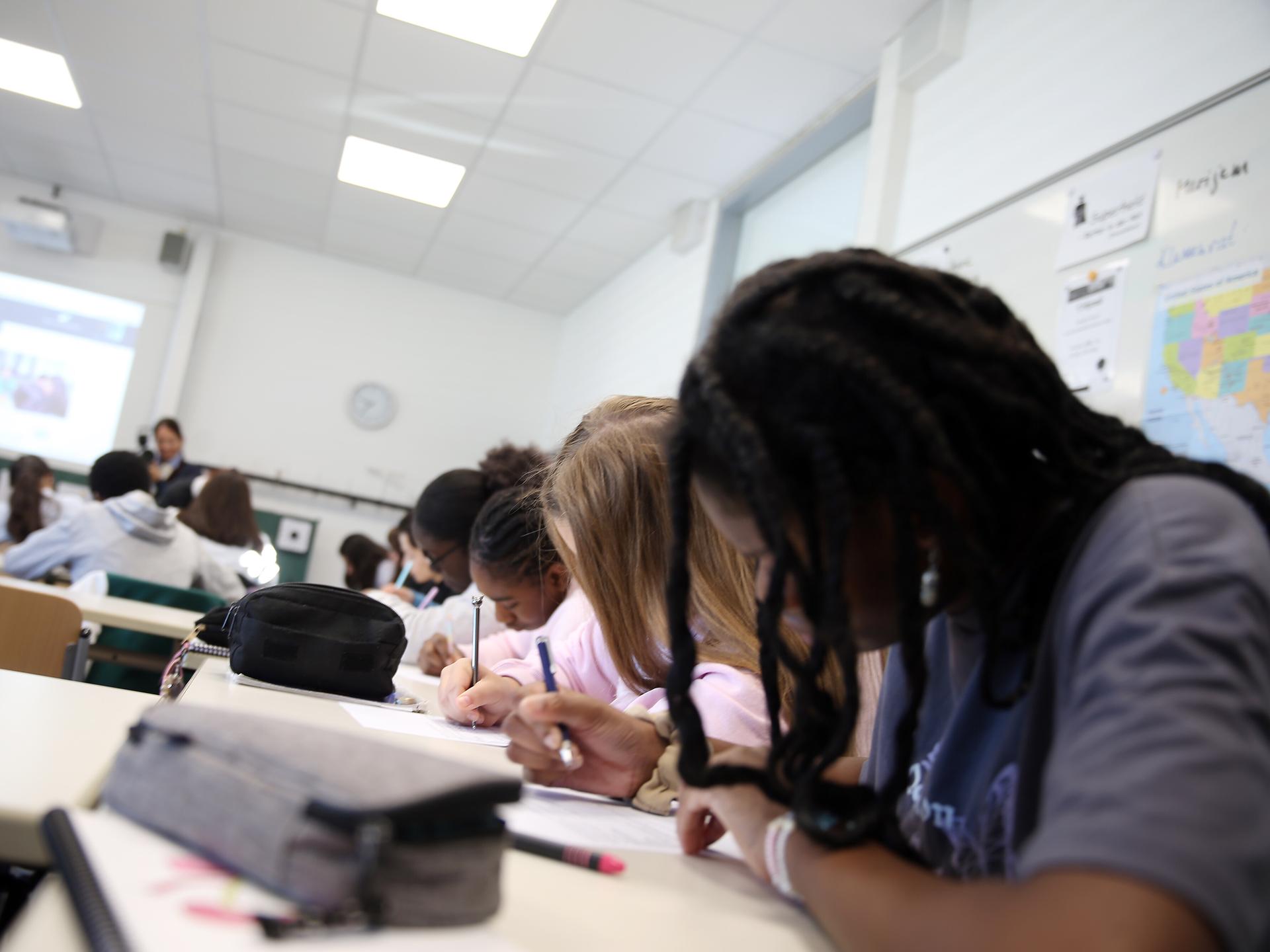 Schüler sitzen während des Unterrichts nebeneinander in einer Klasse und schreiben.